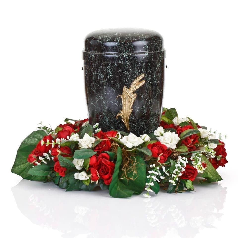 A black urn with flowers around it on top of a table.