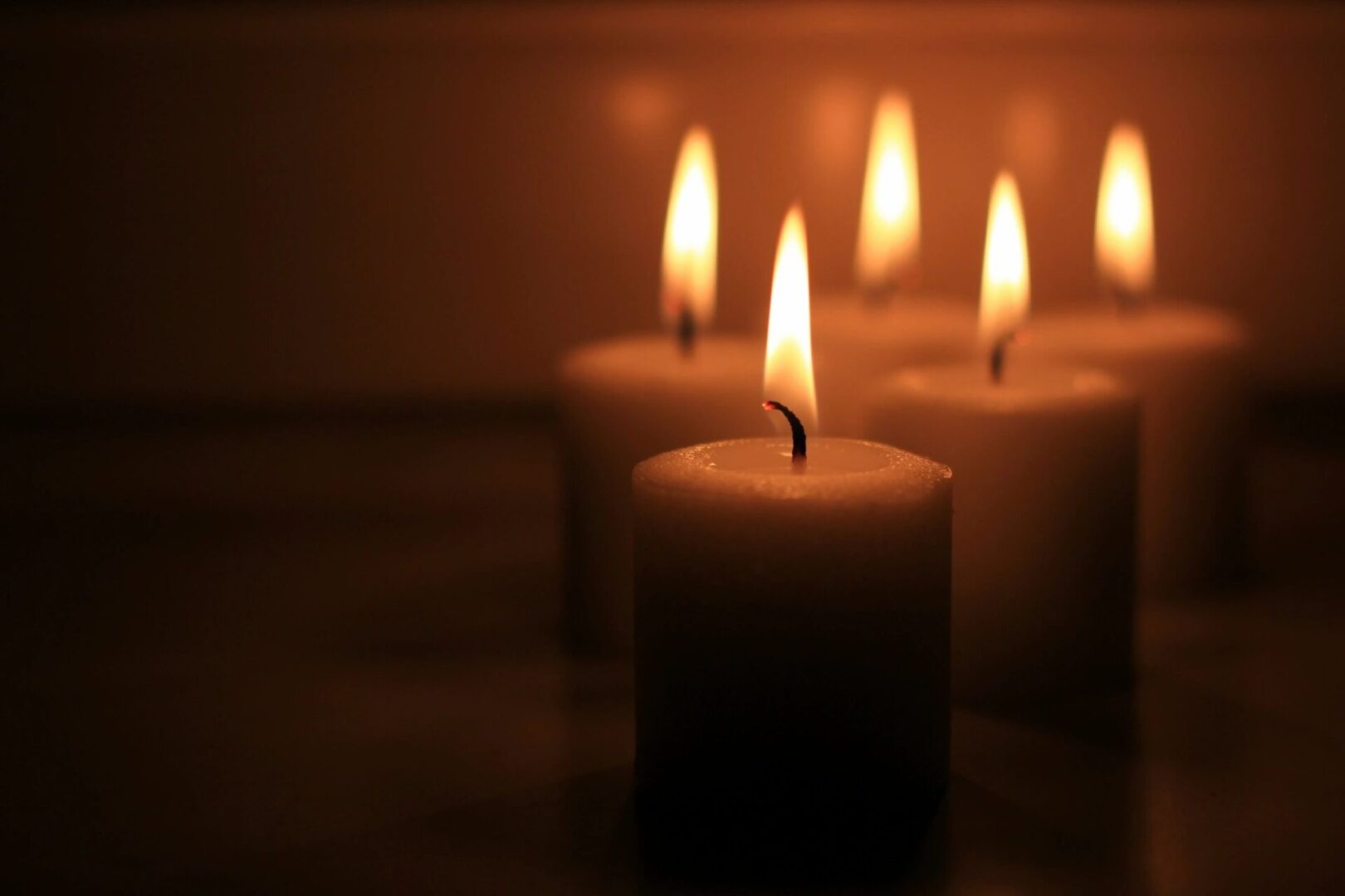 A group of candles lit in the dark.