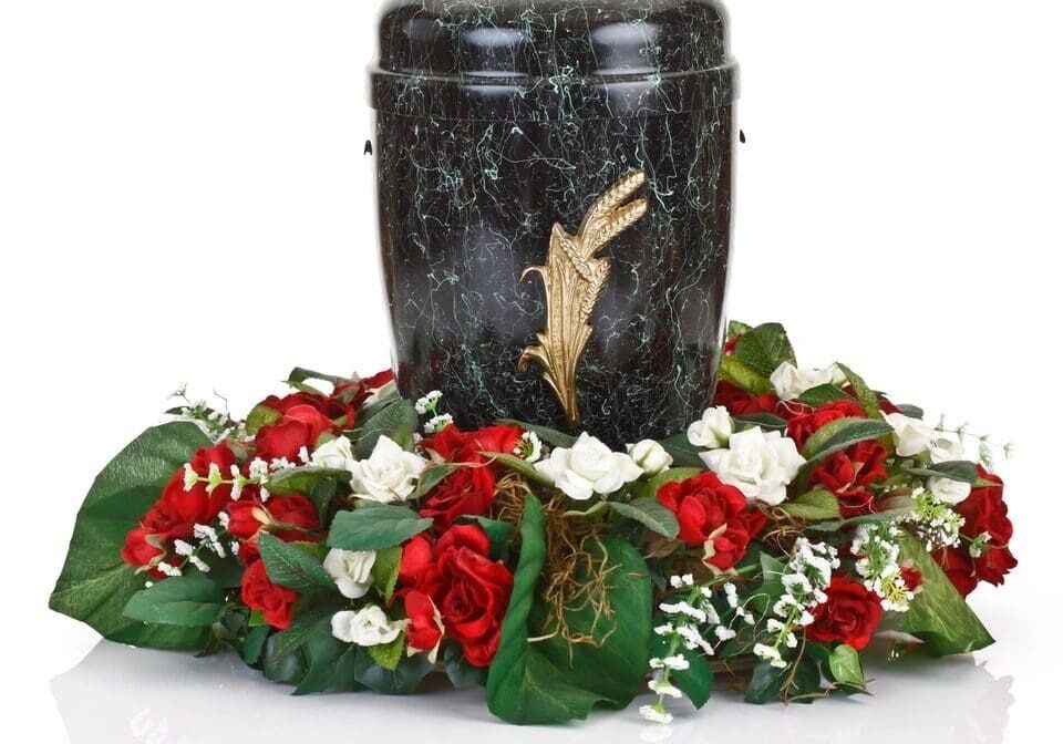 A black urn with flowers around it on top of a table.