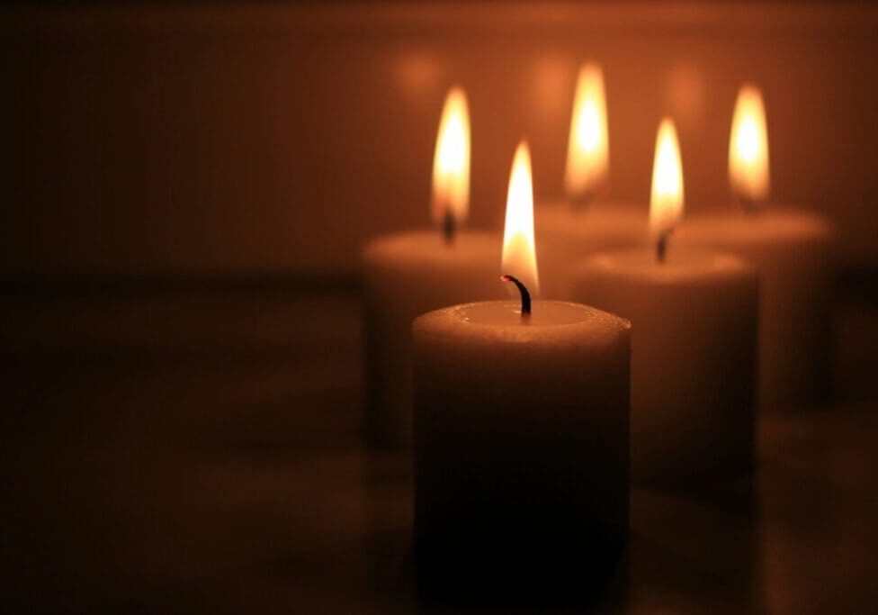 A group of candles lit in the dark.